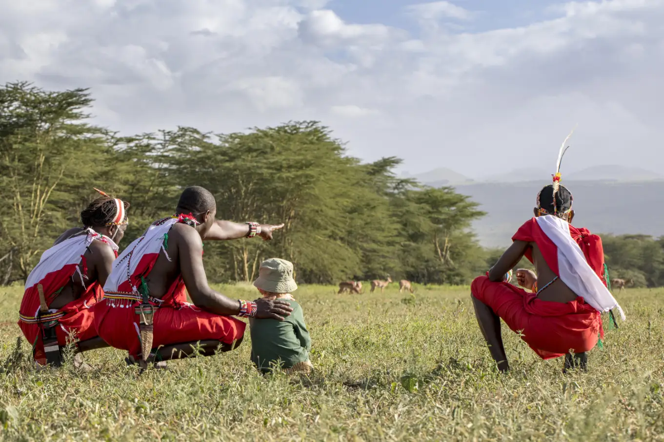 A kid engaging with people in traditional dress during a cultural luxury family safari in Kenya