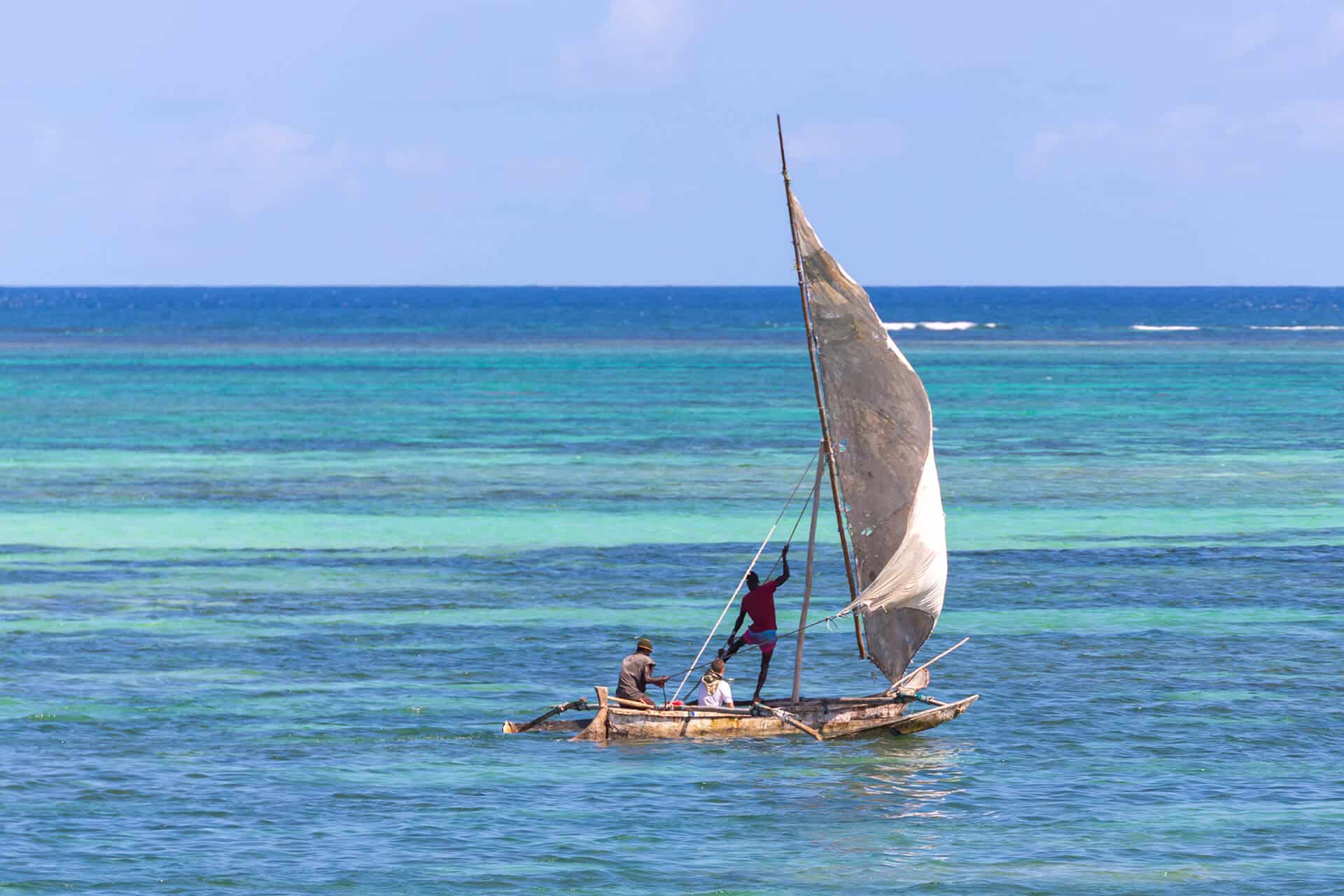 Person sailing with tour guides over clear blue water on the Kenyan ocean, African safari.