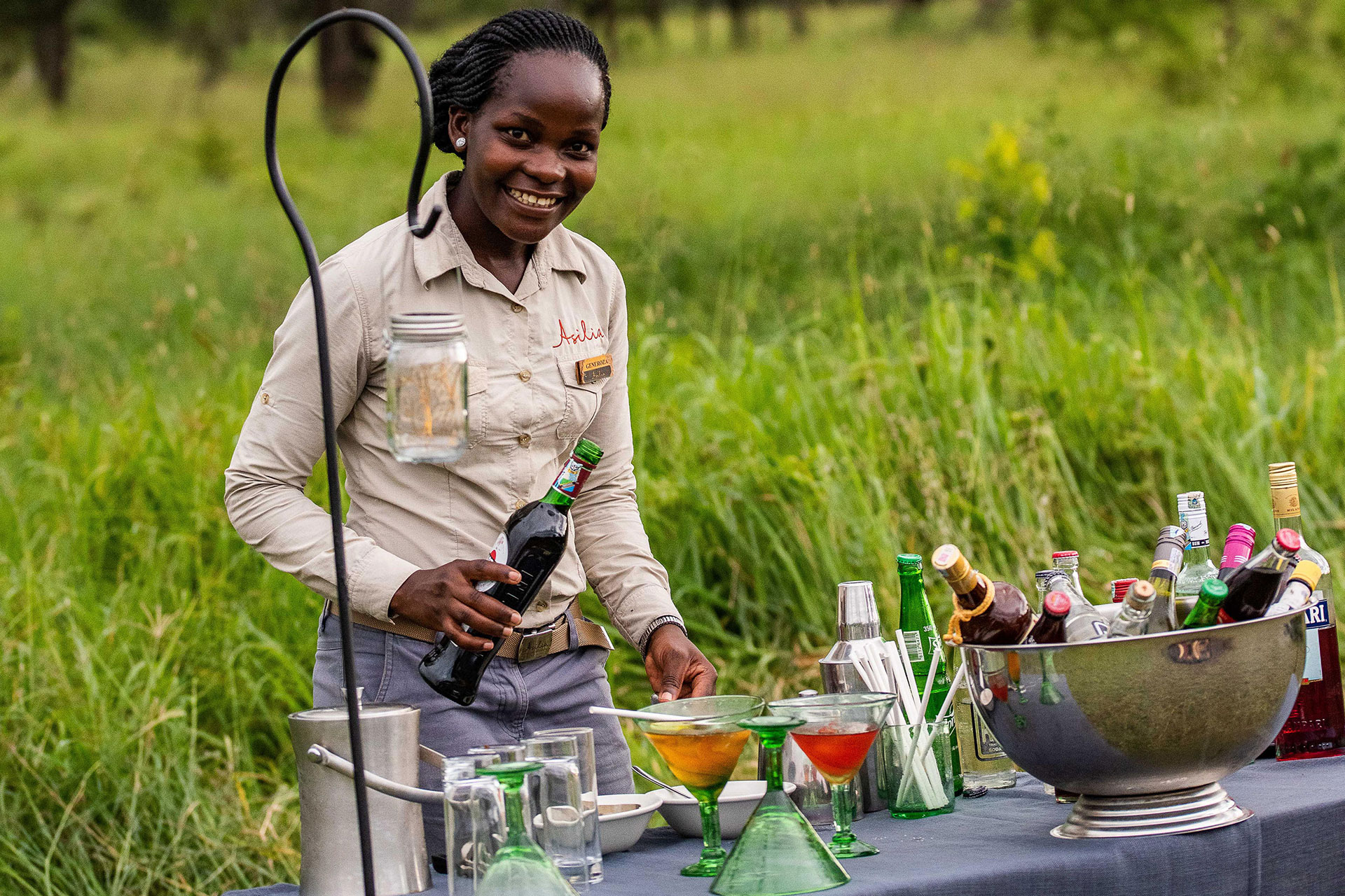 Female guide setting up sunset drinks in the bush during a safari game drive at Dunia Camp