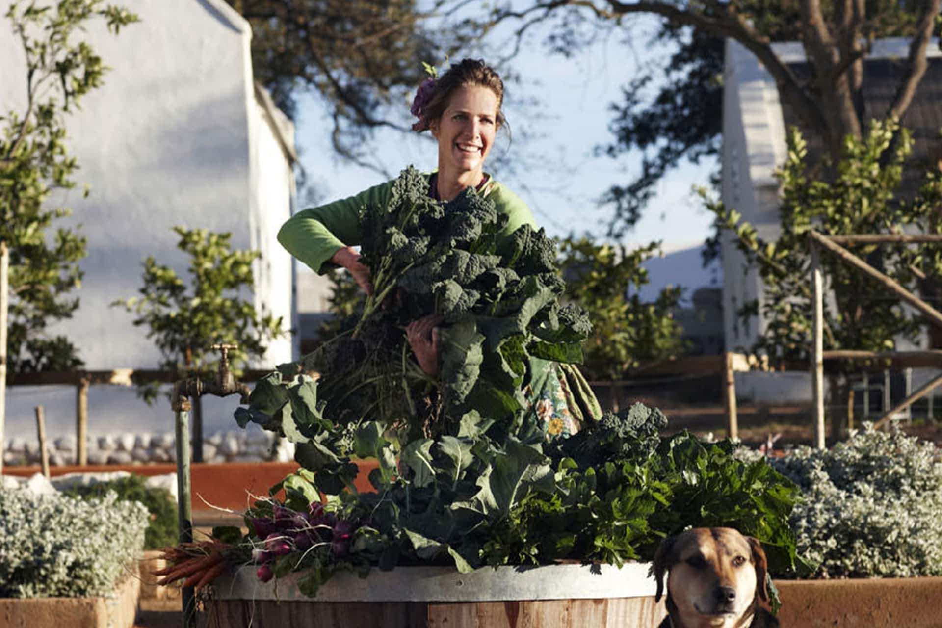 A woman holding fresh produce from Babylonstoren Farm and Hotel