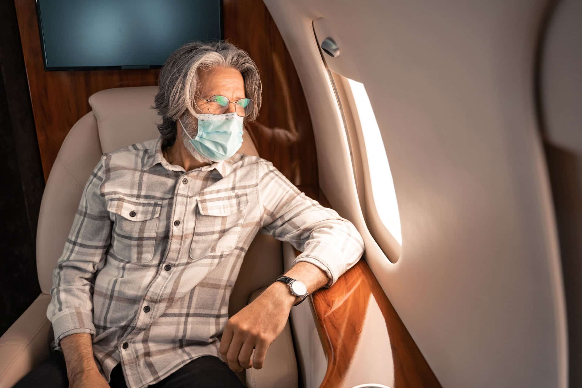A man following COVID-19 safety protocols on a private jet