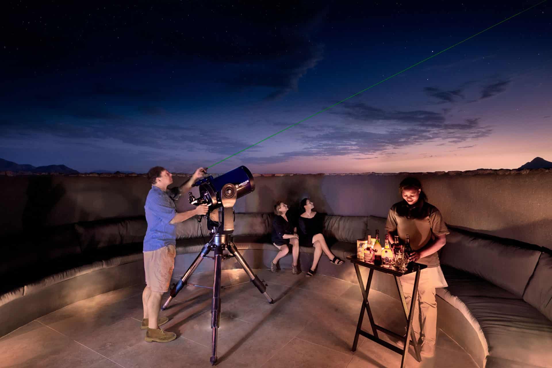 An astronomer with a telescope showing guests the stars in the sky during a night safari andBeyond Sossusvlei Desert Lodge.