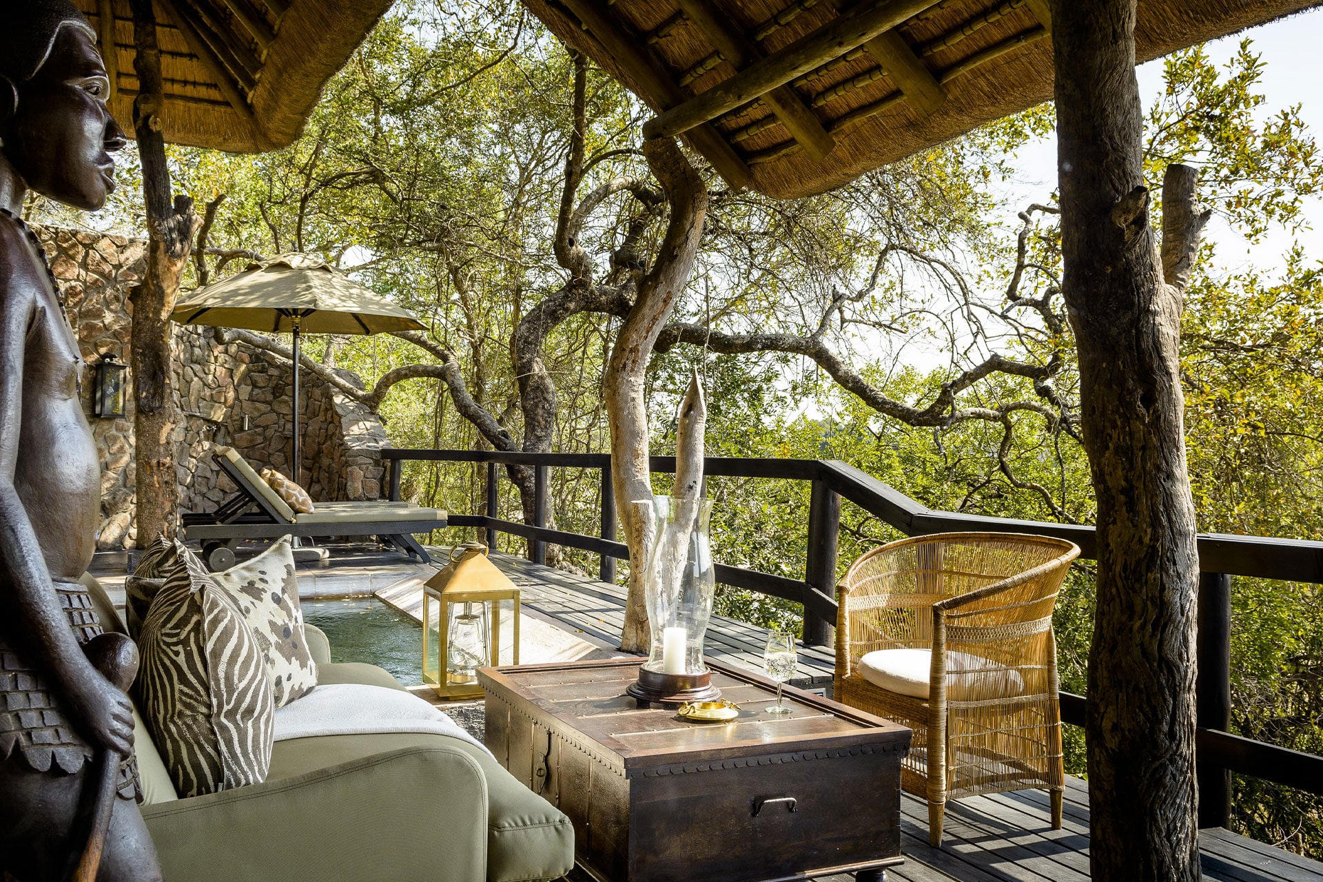 A wooden deck with couches and chairs and a private pool overlooking the Sand River at Singita Sabi Sands Ebony Lodge.