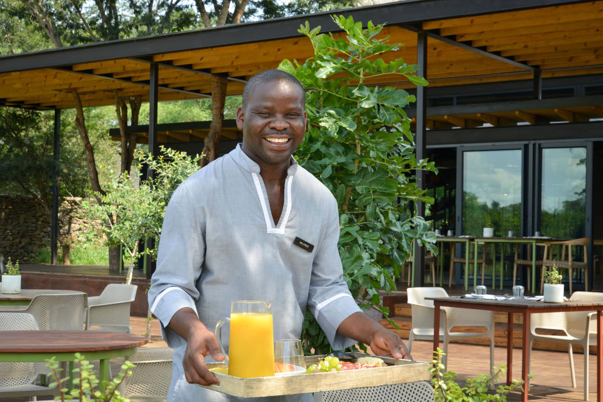 A smiling man holding a tray with a welcome drink at Lion Sands River Lodge in Lion Sands Game Reserve.