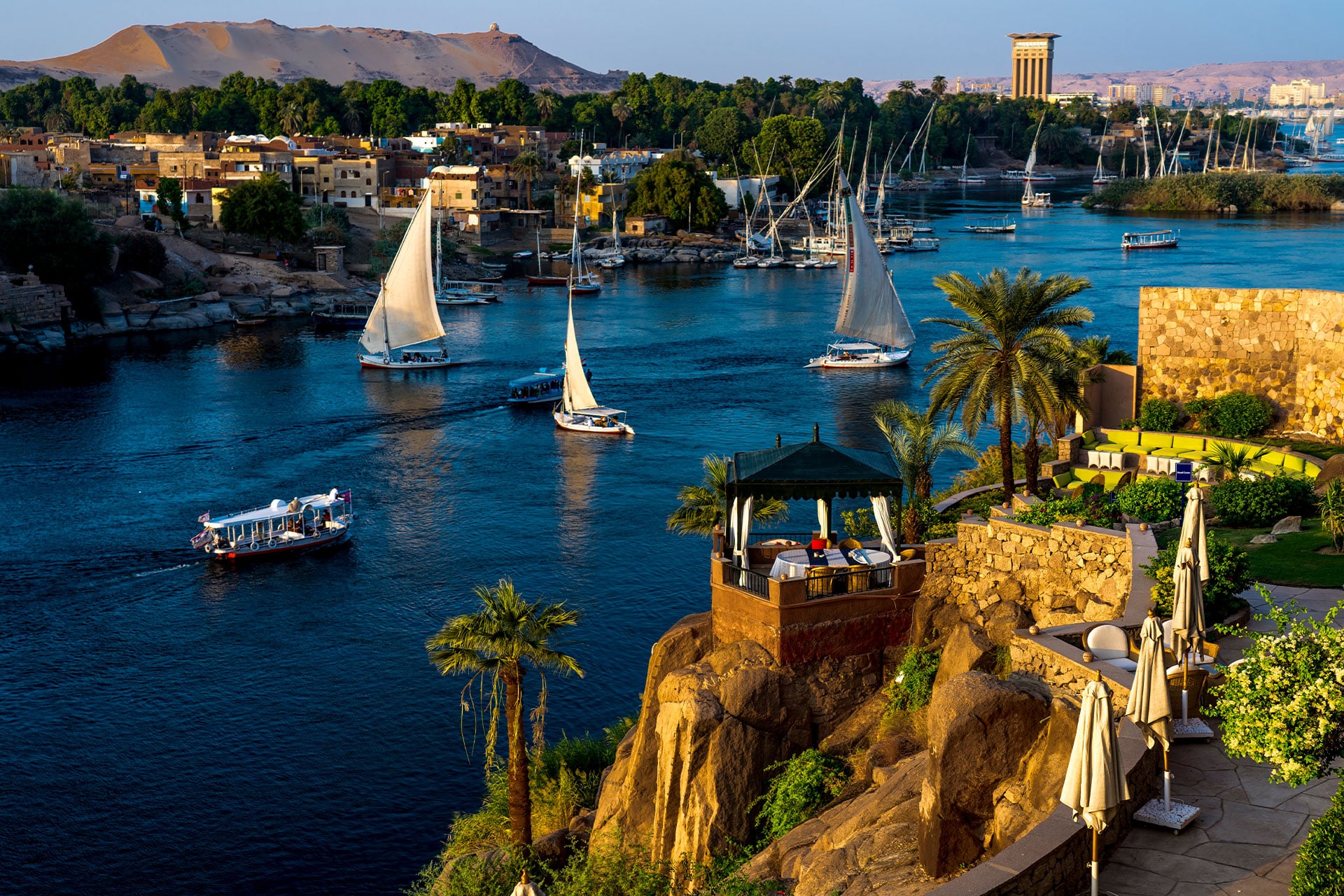 The Nile River flowing through Aswan dotted with cruise boats and feluccas.