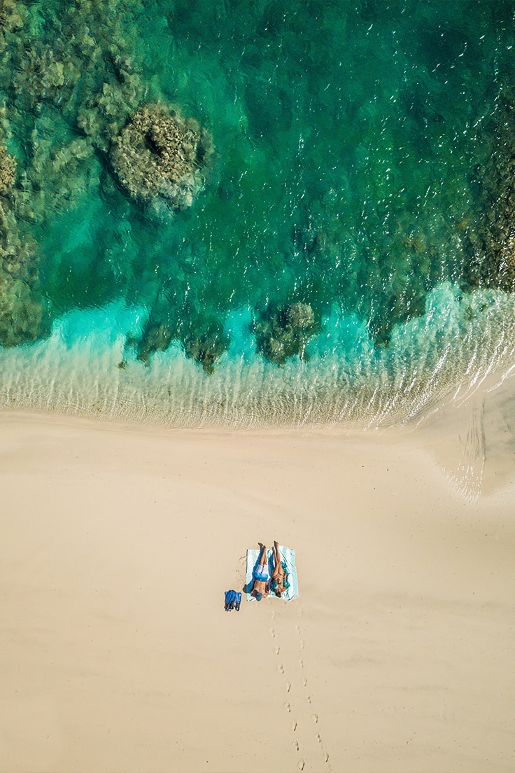 A couple relaxing on the beach after snorkeling at Miavana – a recommended experience for honeymoons in Africa.