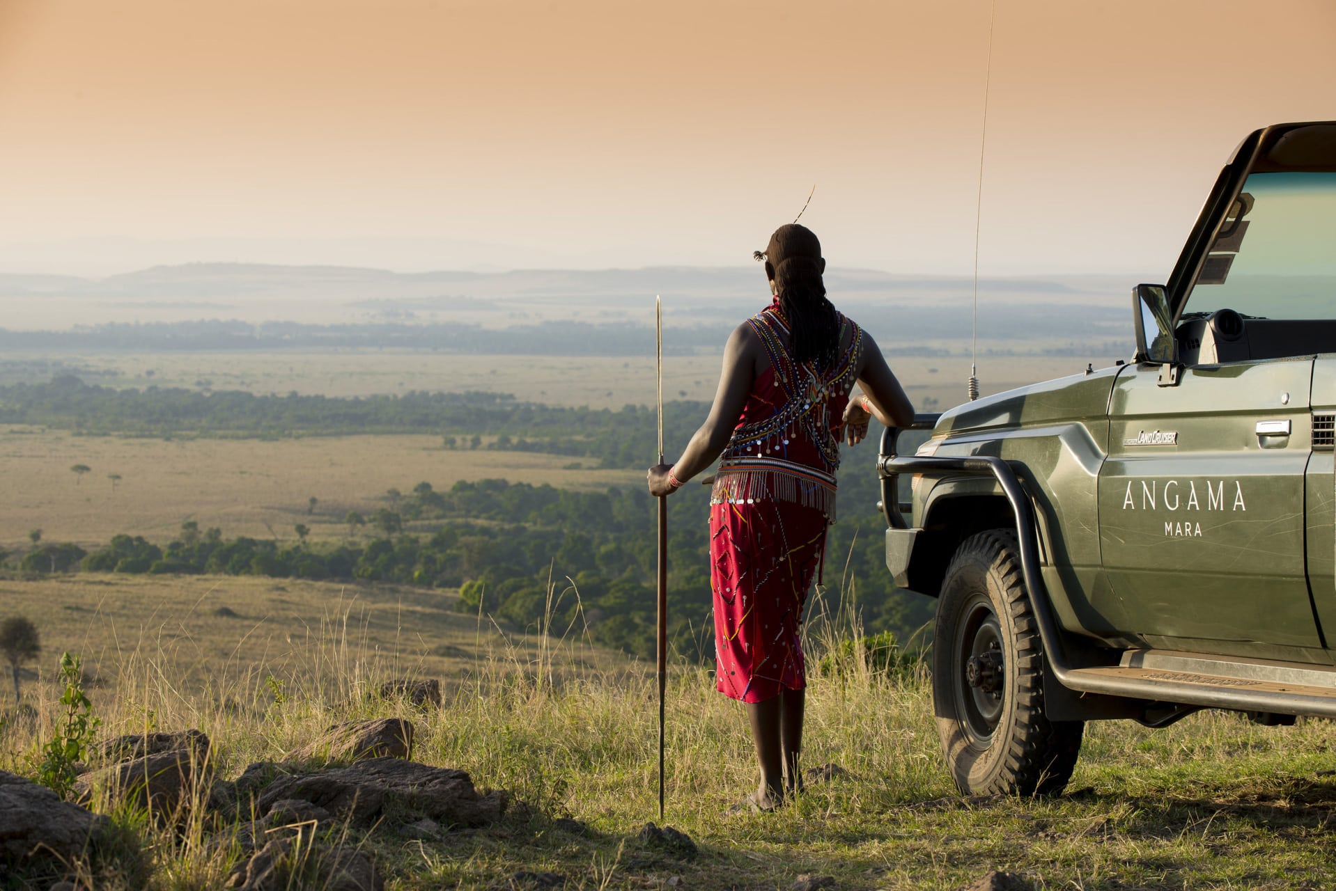 A Maasai warrior leaning on a game drive vehicle at Angama Mara– one of our top rated eco lodges in Africa.
