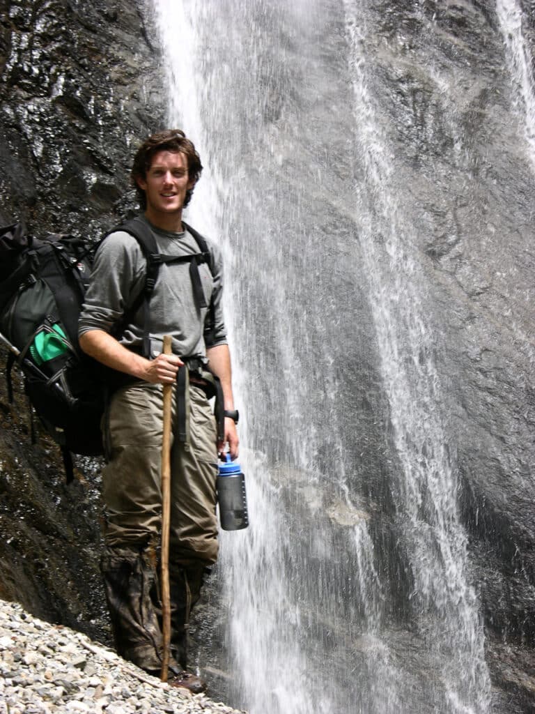 Patrick Woodhead standing next to a waterfall in Tibet.