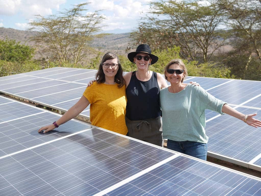 Dr. Delphine Malleret King and some team members leaning on solar panels in Kenya.