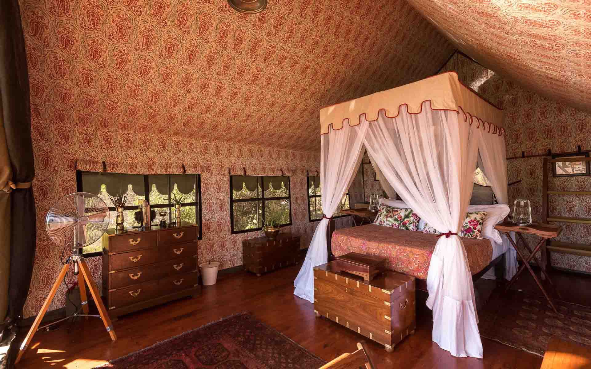 The interior of a luxury double tent with an antique 4 poster bed frame at Duke’s Camp