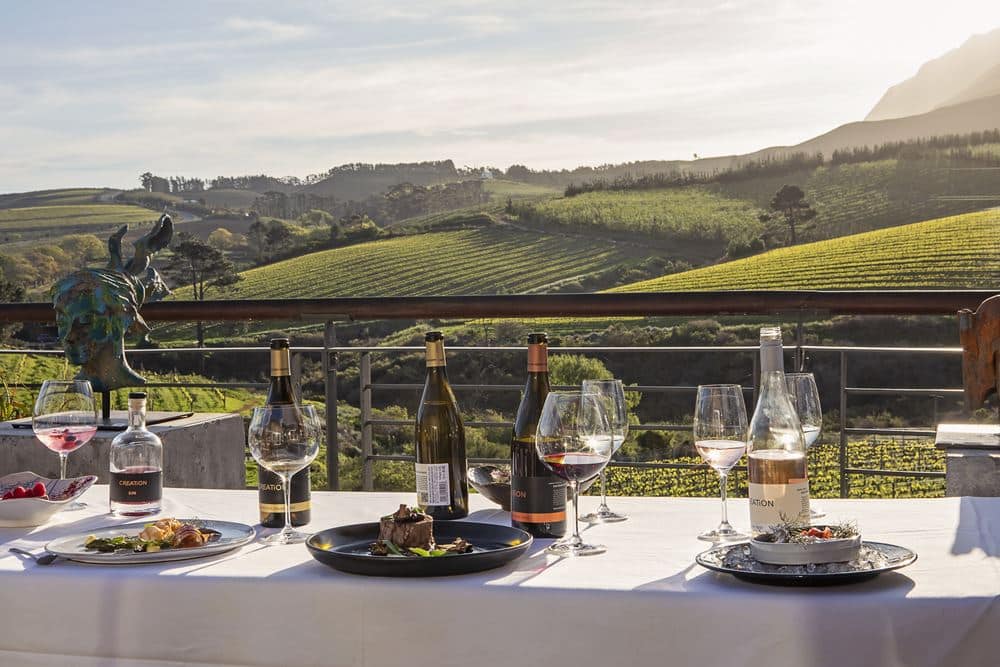 Food and wine on a table overlooking a vineyard with Ker & Downey® Africa