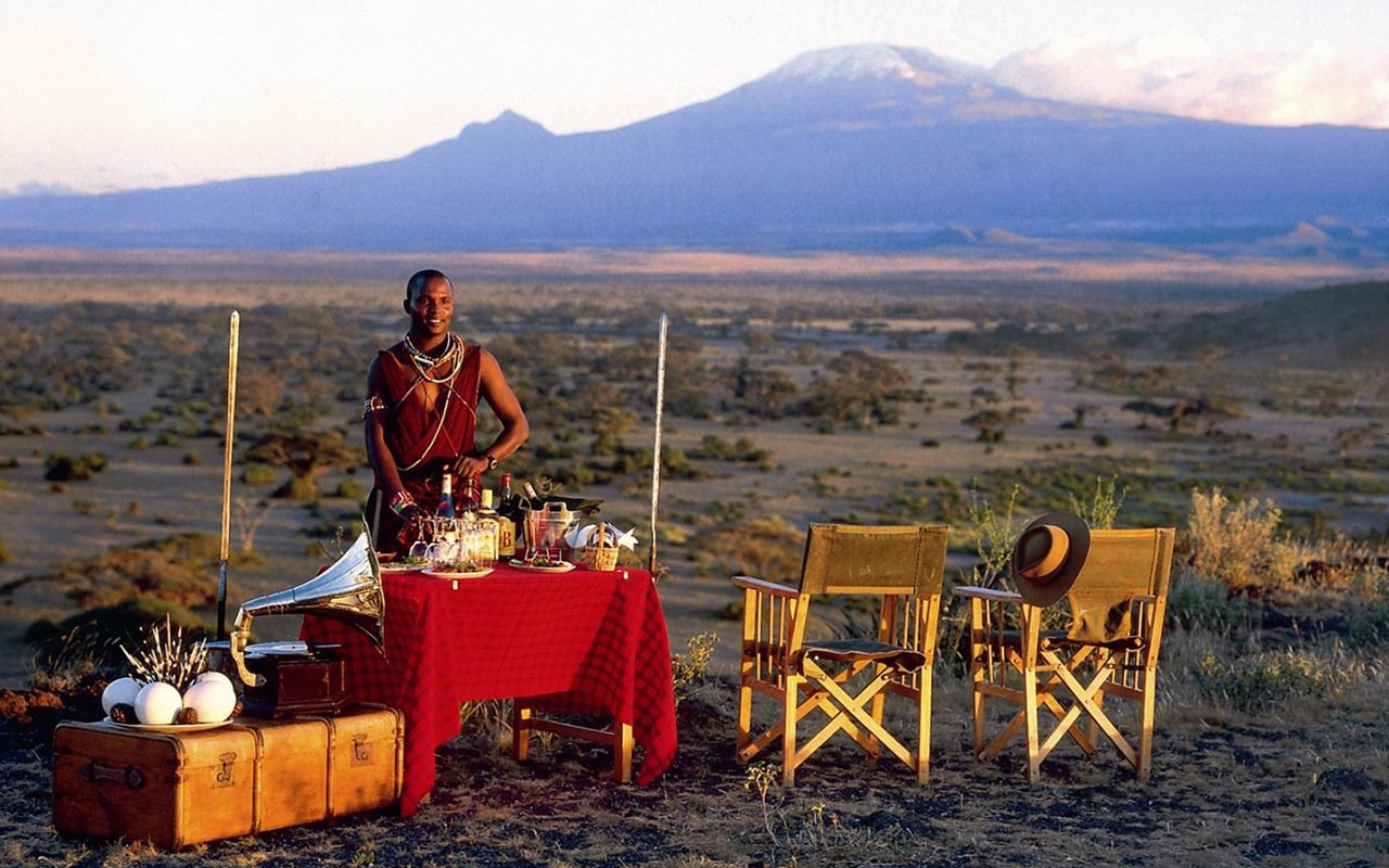 A Maasai man welcoming guests for sundowners at Elewana Tortilis with Ker & Downey® Africa