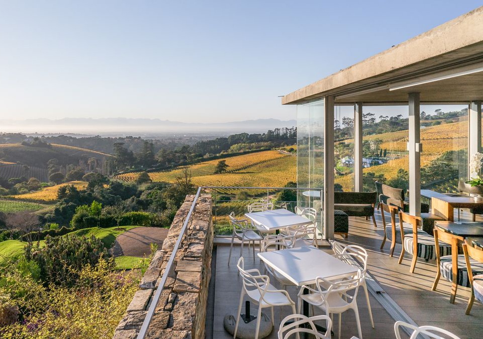 Chairs and table on a deck overlooking Beau Constantia with Ker & Downey® Africa