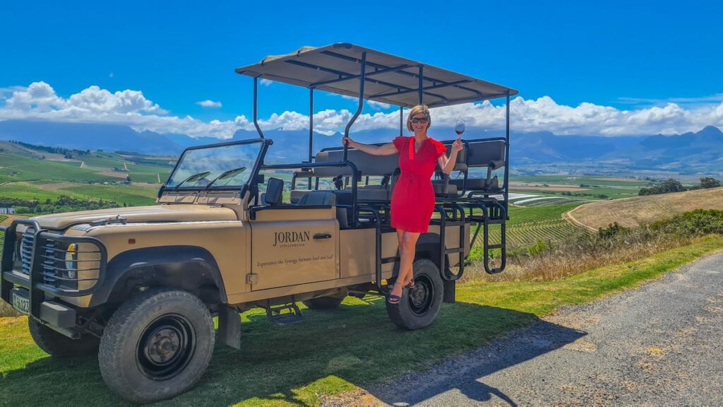 Woman on safari vehicle in front of mountains and vineyards with Ker & Downey® Africa