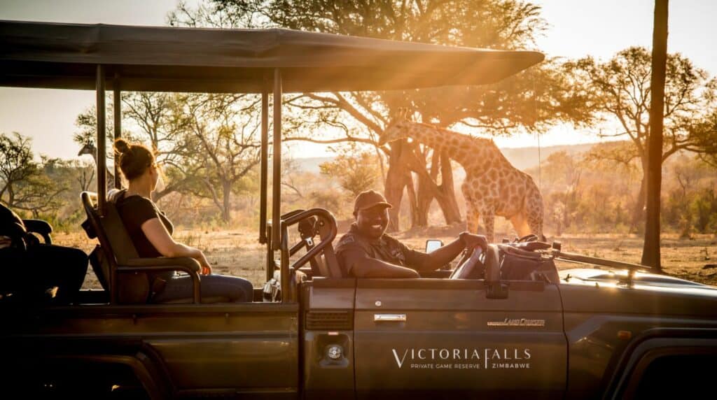a game drive vehicle with a smiling guide at Stanley & Livingstone Boutique Hotel