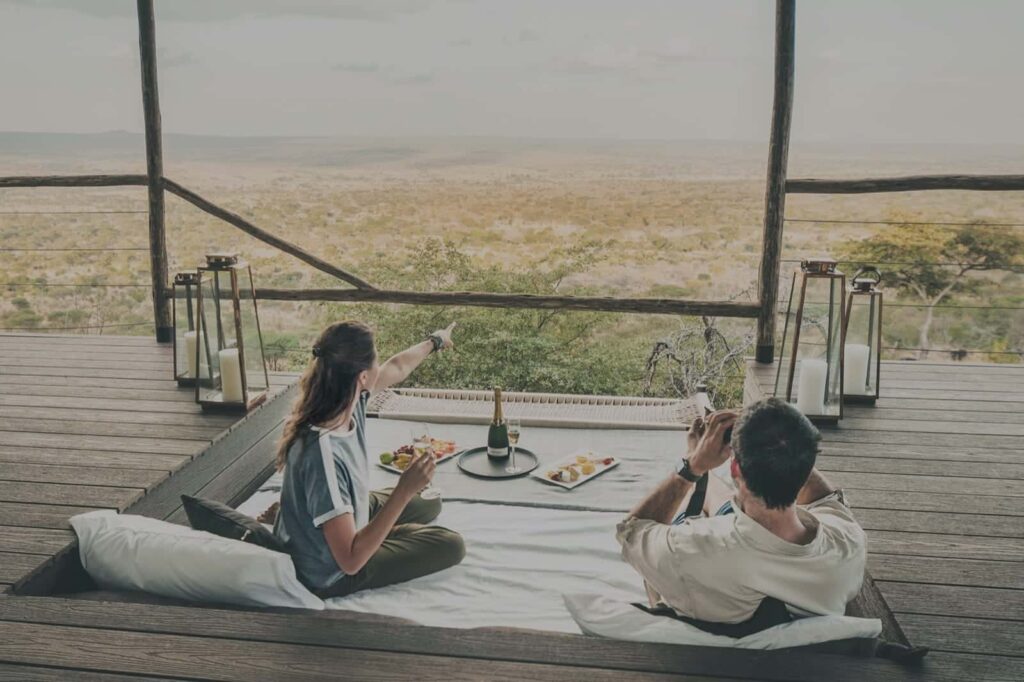 Couple enjoying a romantic meal and panoramic views from a cozy terrace setup during their honeymoon in Tanzania.