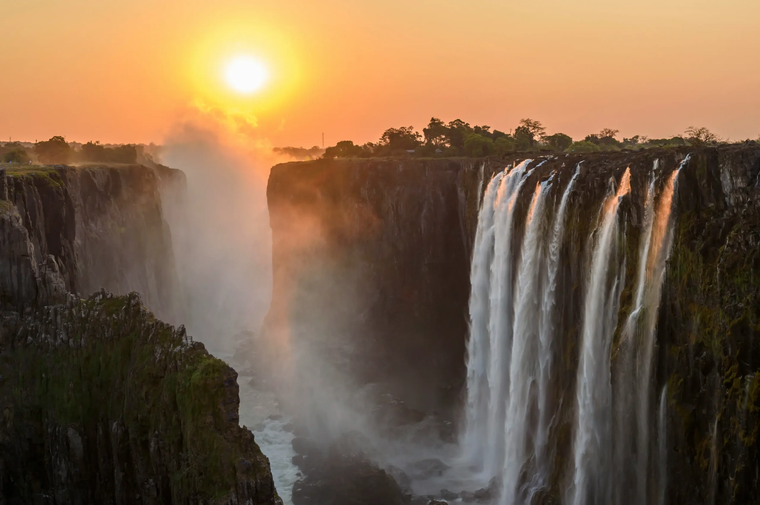 Ultra luxury African safari at Victoria Falls during golden sunset with dramatic mist rising over the Batoka Gorge