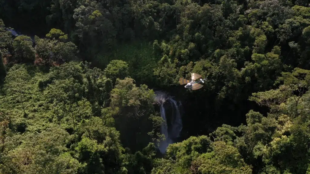 Luxury safaris by air Africa helicopter flying over lush rainforest and waterfall on an exclusive aerial safari experience