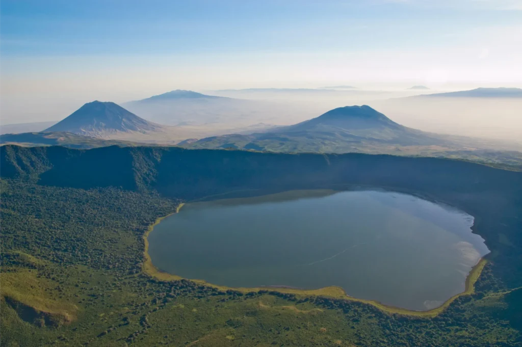 Aerial view of a volcanic crater lake surrounded by lush green highlands during Africa’s Secret Season, showcasing dramatic landscapes and soft morning light