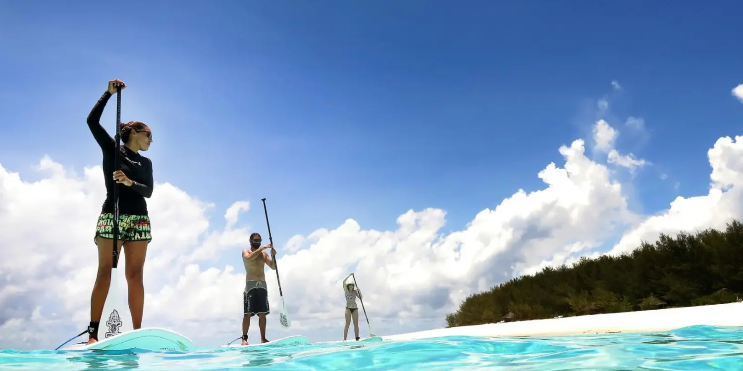 Stand-up paddleboarding in turquoise waters off the shores of &Beyond Mnemba Island.