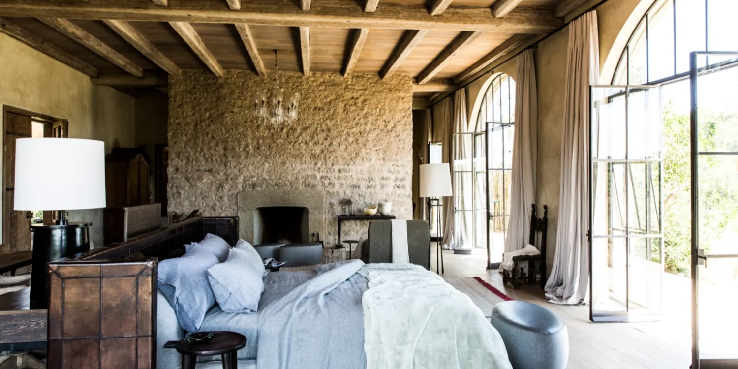Elegant bedroom suite inside private safari villas featuring stone walls, high ceilings, and panoramic bush views