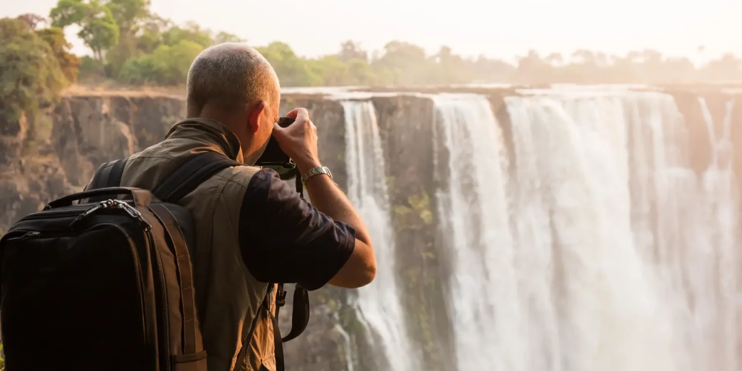 Photographer capturing Victoria Falls in misty golden light during Africa’s Secret Season, with powerful cascading waterfalls along the Zimbabwe-Zambia border