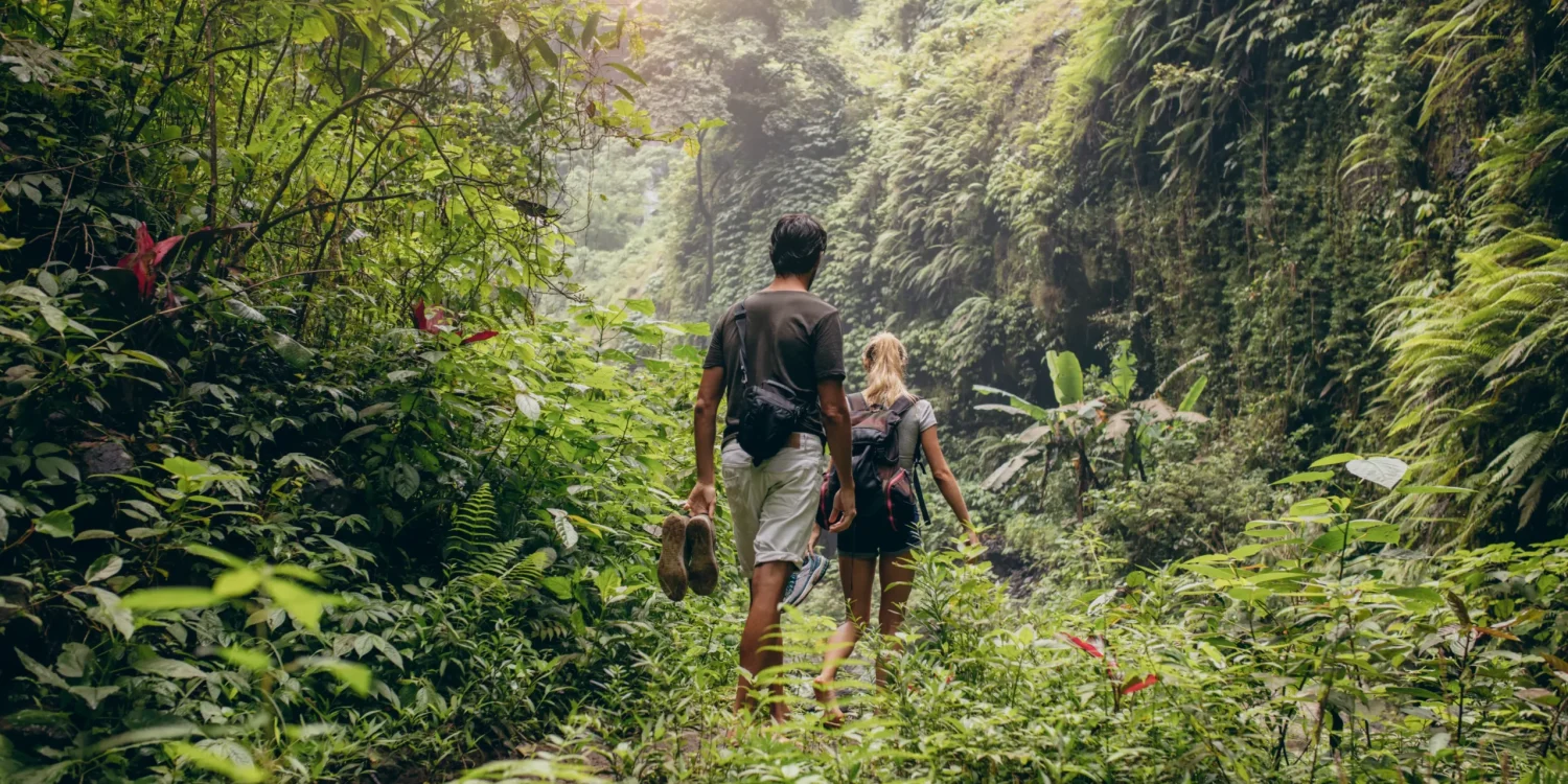 Casal caminhando por uma exuberante floresta tropical durante um safári em setembro, em Ruanda.