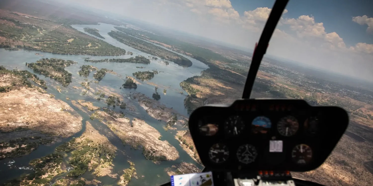 Luxury safaris by air Africa scenic helicopter flight over winding river channels and dramatic landscapes from the cockpit view