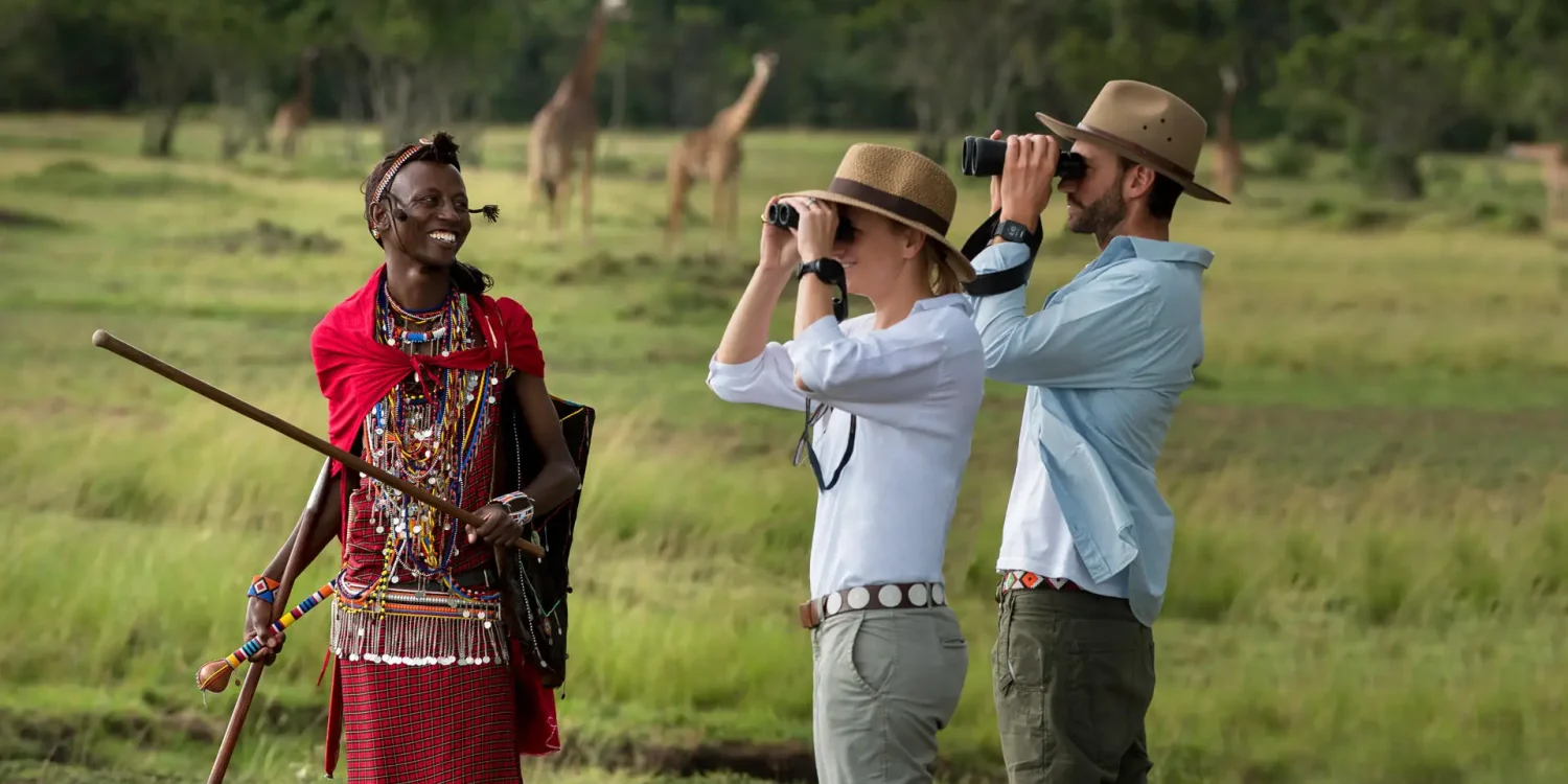 Tourists spotting giraffes with Maasai guide during the best time to visit the Masai Mara safari season