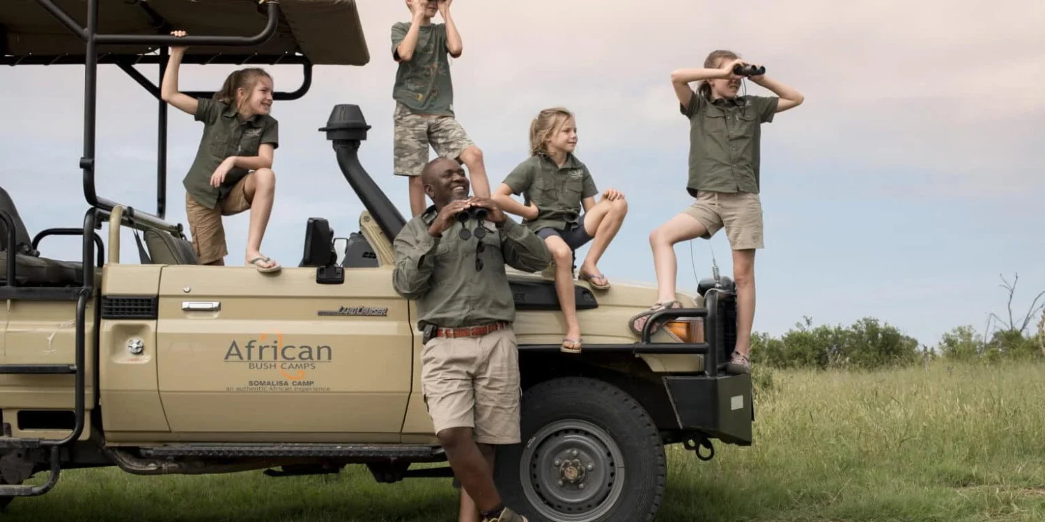 children with safari guide on a jeep during a school summer holiday adventure in the bush.