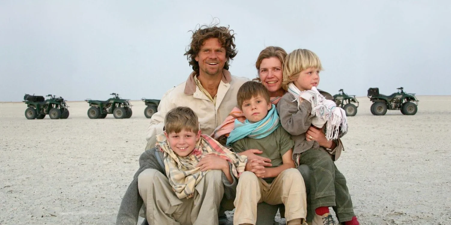 family posing together in the desert during a family safari adventure, with quad bikes in the background.