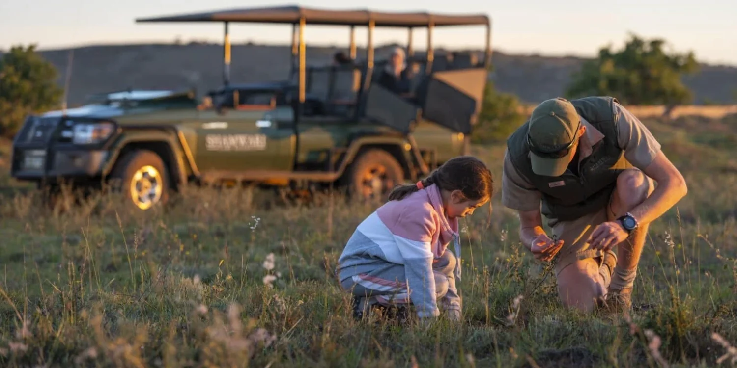 child with safari guide examining nature during a jeep safari school outing on spring break.