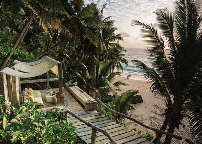 Private deck overlooking the ocean at North Island, featuring a luxury beachfront villa surrounded by palm trees on exotic Islands in Africa